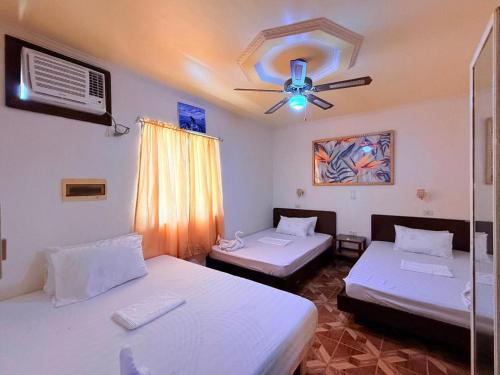 a room with two beds and a ceiling fan at Cocomango's Resort in Taporok