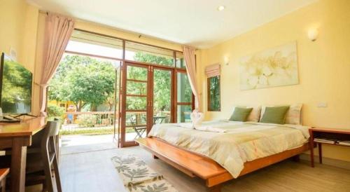 a bedroom with a bed and a desk and a window at Doembang Villa in Ban Tha Pong