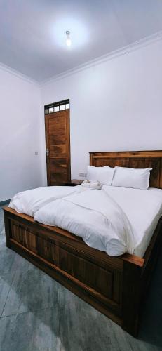 a bedroom with a large wooden bed with white sheets at chama haven apartments in Nkoanrua