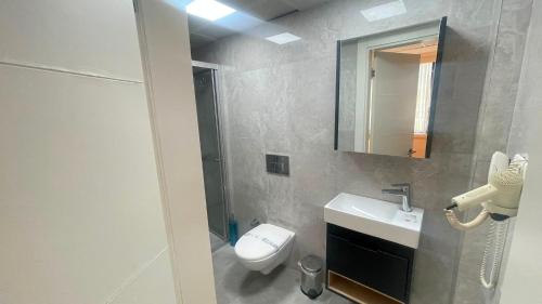 ein Badezimmer mit Toilette, Waschbecken und Spiegel in der Unterkunft Walkin Hotel in Konak