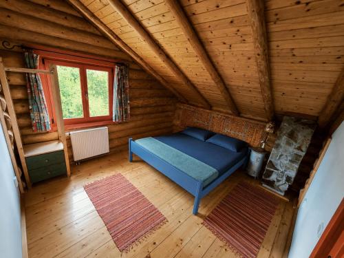 a room with a blue bed in a wooden house at Traditional wooden cottage in Cîmpu Cetăţii