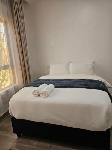 a bedroom with a bed with two towels on it at Luxe Apartments in Lusaka