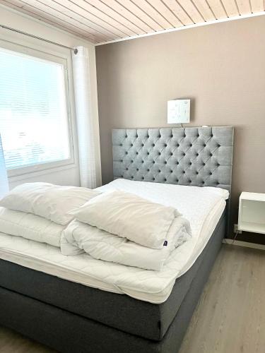 a bedroom with a large bed with white sheets at Kulta Villa, keskellä Vuokattia sisältyy Sauna, ilmainen Pysäköinti, Wi-Fi, 65smartTV, oma pieni piha alue, sopii perheille in Vuokatti