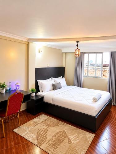 a bedroom with a bed and a desk and a window at Novo Axora Lounge & Accommodation Kimbo Ruiru Kimbo Lopha Stage in Ruiru