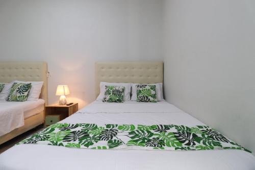 a bedroom with two beds with green and white pillows at Bisma Balcony Homestay in Yogyakarta