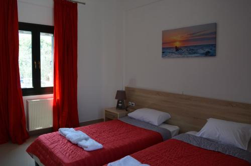 een slaapkamer met 2 bedden en een raam met rode gordijnen bij Villa Marianthi in Petra