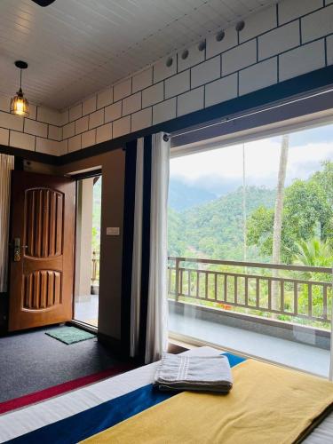 a room with a bed and a balcony with a view at Linn View Home Stay Munnar in Munnar