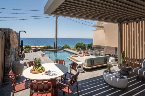 a patio with a table and chairs and a swimming pool at Lapis Nera Villas - Beachfront & "Free" Heated Pools in Psari Forada
