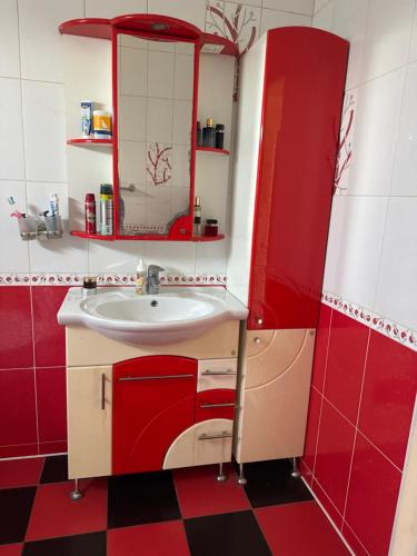 a red and white bathroom with a sink and a mirror at Приватні апартаменти in Odesa