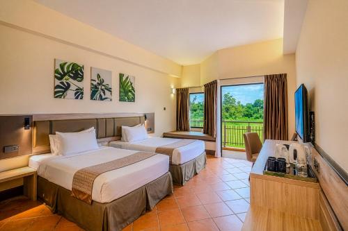a hotel room with two beds and a flat screen tv at Thistle Port Dickson Resort in Port Dickson