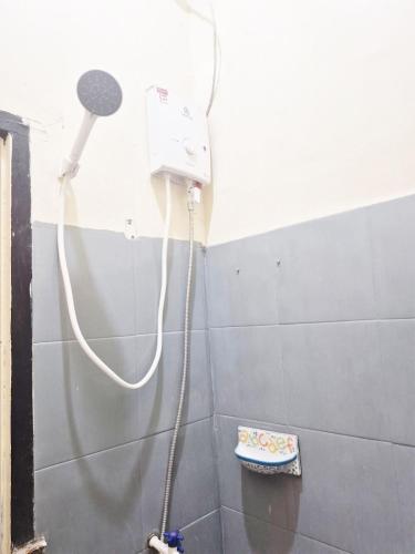 a shower head with a hose attached to a wall at Kos Mama Ros in Labuan Bajo