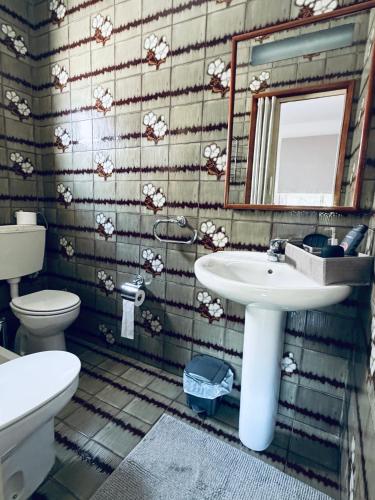 a bathroom with a sink and a toilet and a mirror at Moradia Vila Real Sto Antonio in Vila Real de Santo António