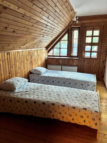 two beds in a room with wooden walls and windows at Võsula Tornimaja apartments in Võsu