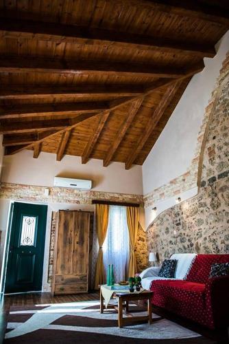 a living room with a red couch and a table at Jason's Stone House in Ágios Matthaíos