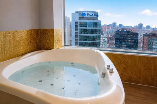 a bath tub in a bathroom with a view of a city at Seven Eleven Apartment HOTEL in Most City in Dnipro