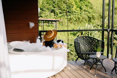 a woman sitting in a bath tub on a deck at Grey Rock Mountain Cabin w/ Jacuzzi in Balamban
