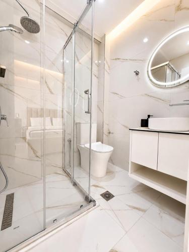 a white bathroom with a shower and a toilet at Apartment Katherina Sarande in Sarandë