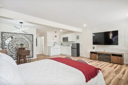 a white bedroom with a large bed and a kitchen at Clair de Lune Studio A Charming Kokomo Stay in Kokomo