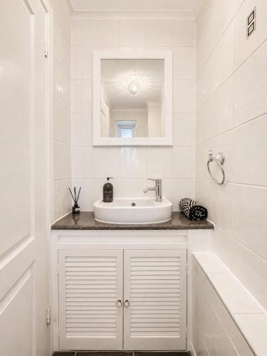 a white bathroom with a sink and a mirror at Three Bed Detached Property in Frimley