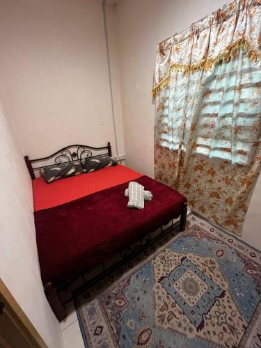 a bedroom with a red bed and a window at Homestay Seri Aishah in Chemor