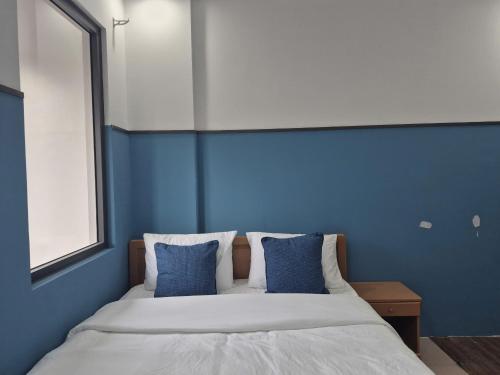a blue bedroom with a bed with blue walls at Hyper house hotel in Buôn Ðũng