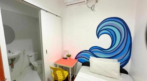 a bathroom with a painting of a wave on the wall at Dormitelsph BGC in Manila