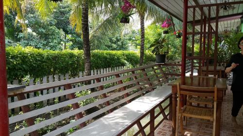a woman sitting at a table on a porch at Warakorn Baansuan Amphawa in Amphawa