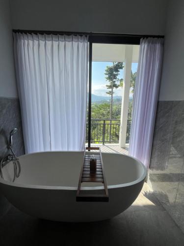 a bath tub in a bathroom with a large window at Sidemen padi villas in Silebeng