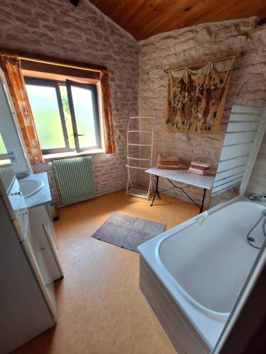 a bathroom with a tub and a table and a window at La Ferme du Marais Poitevin - Chambre d'hôtes in Benet