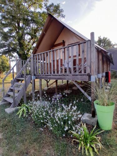 a small house with a porch and some flowers at Camping Port la Vallée in Saint-Mathurin