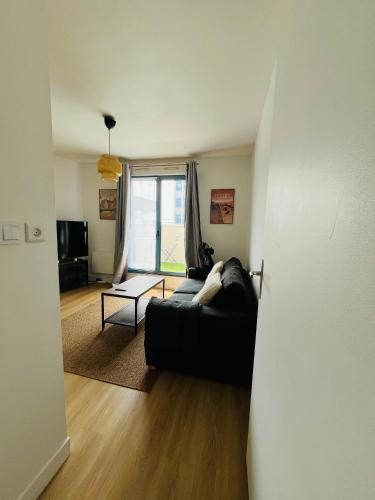 a living room with a black couch and a window at Le cocon Panoramique in Tours
