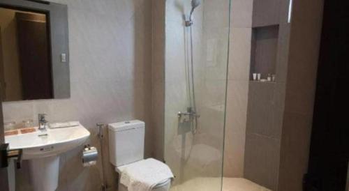 a bathroom with a shower and a toilet and a sink at Maxx Hotel Ortigas in Manila