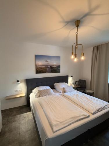 a bedroom with a bed and a chandelier at Hotel Haus Hubertus in Schneverdingen