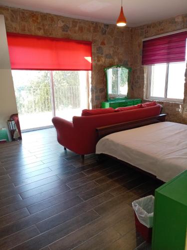 a bedroom with a large bed and a red couch at Khalle lodge in Dayr al Qamar