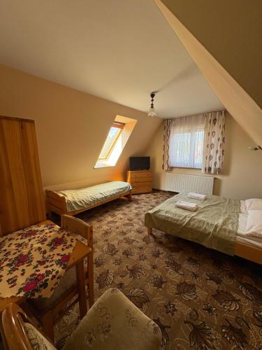 a bedroom with two beds and a table and a chair at Dom Wypoczynkowy Maniek in Białka Tatrzańska