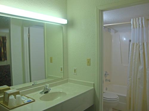 a bathroom with a sink and a toilet and a mirror at Plaza Inn in Topeka