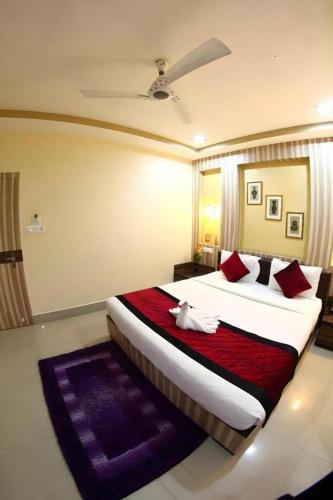 a bedroom with a large bed with red pillows at Mayor Hotel in Siliguri