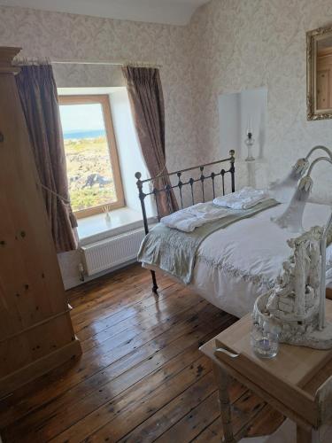 a bedroom with a bed and a window and a table at The Point by the Sea in Carraroe