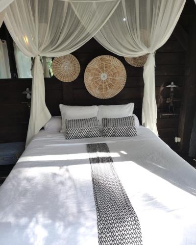 a white bed with curtains and pillows on it at Cabanes et Spa Les Landines in Origne