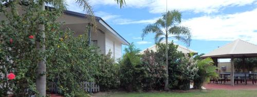 una casa con árboles, una mesa y un edificio en Matildas End Holiday Units, en Karumba