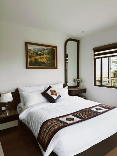 a bedroom with a white bed with a picture on the wall at Sun Hill Villa in Lao Cai
