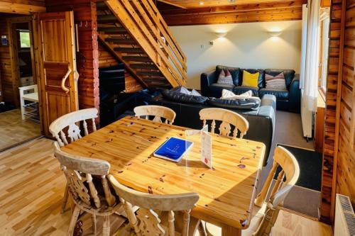 a dining room with a wooden table and a couch at Tor View Lodge with Hot Tub & Sauna - Spa Resort - South Devon in Chudleigh