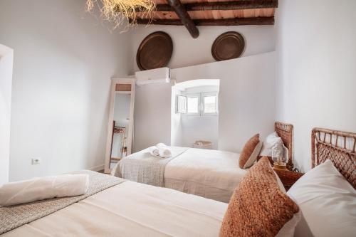 two beds in a room with white walls at Refúgio da Mel - Piscinas e Praia fluvial próximas in Alandroal