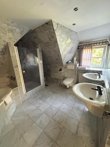 a bathroom with two sinks and a shower and a toilet at Hotel Haus Hubertus in Schneverdingen
