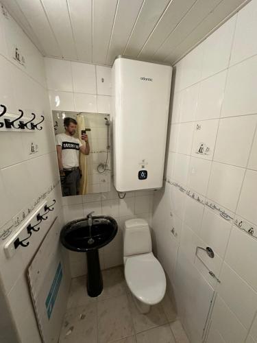 a man taking a picture of a bathroom with a toilet and sink at Ottenson Saaremaa apartment in Salme