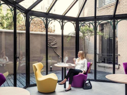 a woman sitting at a table in a glass house at Mercure Paris Alesia in Paris