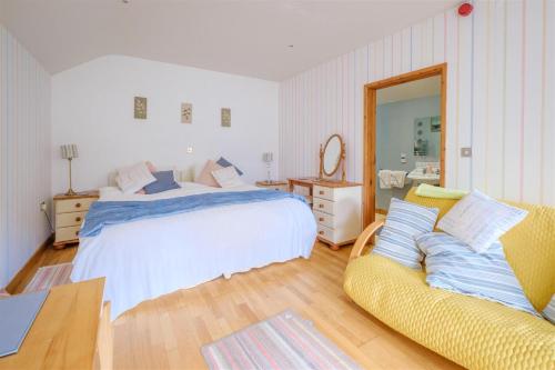 a bedroom with a bed and a couch and a mirror at Down Ende House Accommodation in Looe