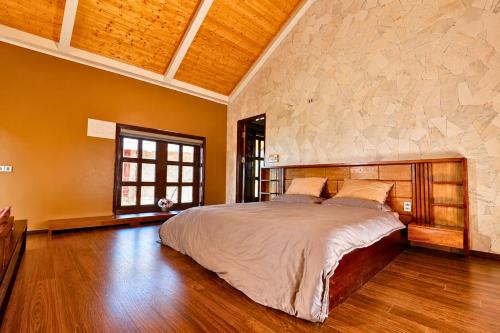 a bedroom with a large bed and a stone wall at Cloud Paradise Resort in Lao Cai