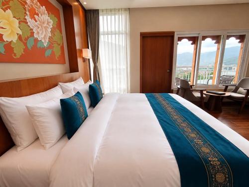 a bedroom with a large white bed with blue pillows at Tshang RI in Thimphu
