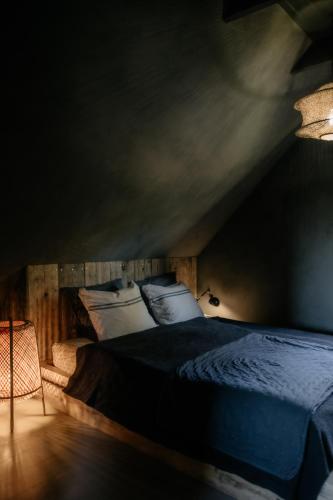 a bedroom with a bed with blue sheets and pillows at Flumen MIkoszewo in Skorka